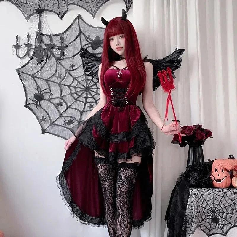 Person in a Halloween costume with red hair and black wings, standing in front of a spider web and pumpkins.